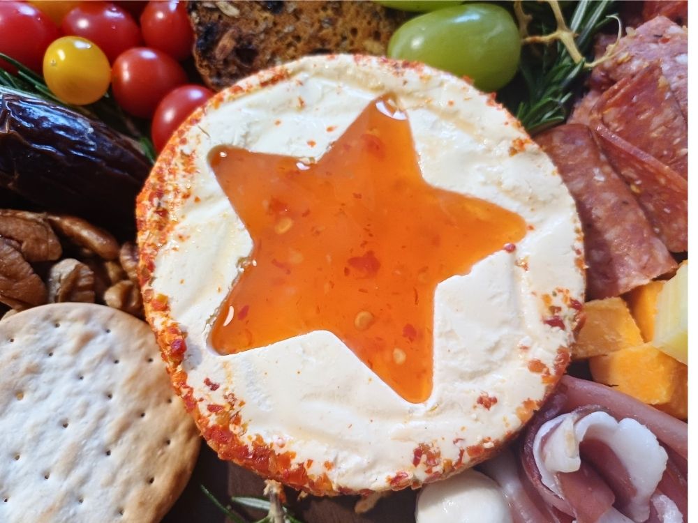 A cream cheese wheel star shape filled in with sweet chilli sauce