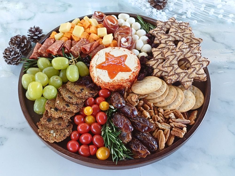 Round Christmas wreath charcuterie board filled with cured meats, cheeses and fruits