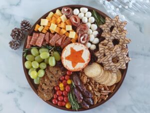Arrangement of cured meats, cheeses and fruits on a round charcuterie board, Christmas festive decoration