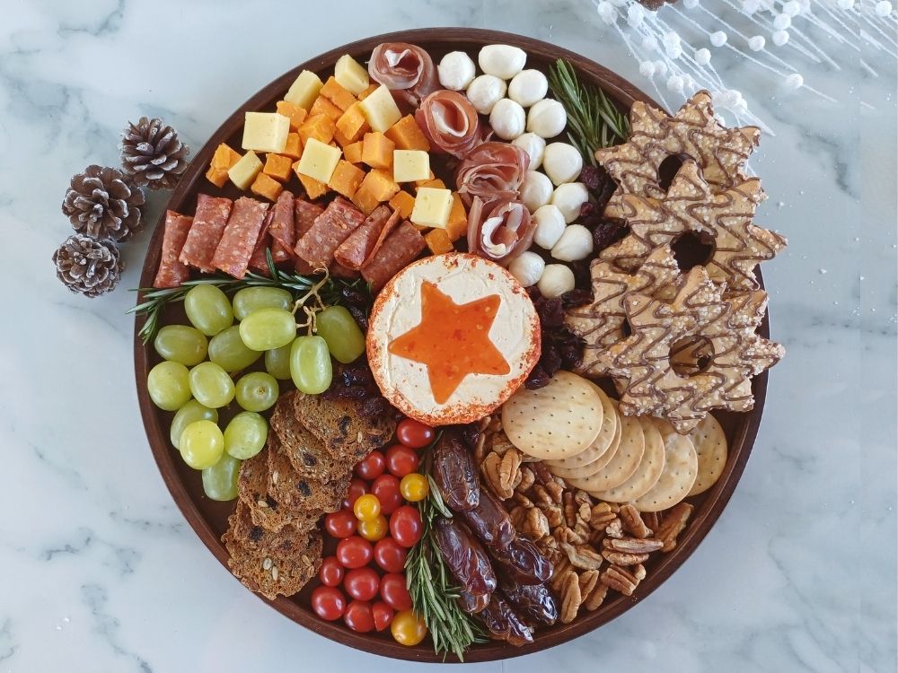 Arrangement of cured meats, cheeses and fruits on a round charcuterie board, Christmas festive decoration
