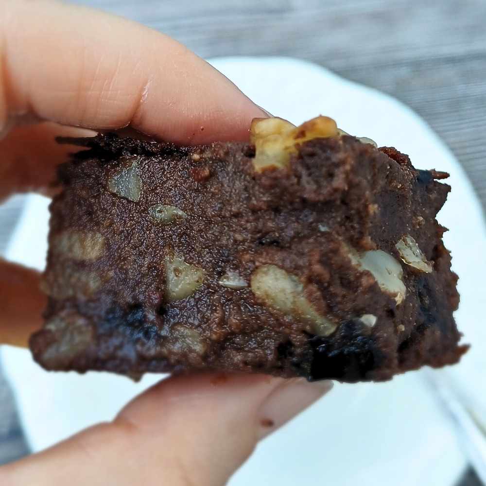 A piece of almon flour brownies with macadamia nuts inside