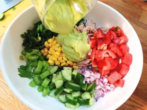 pouring avocado dressing over the healthy tuna salad