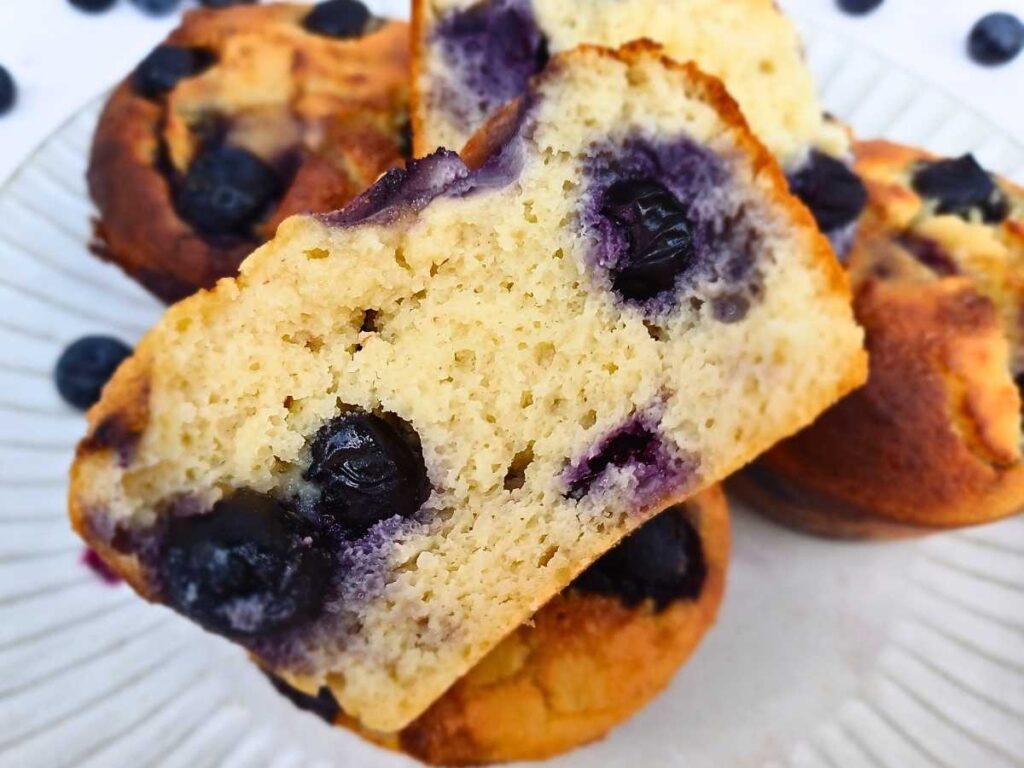 A broken almond flour muffins with blueberries showing soft center