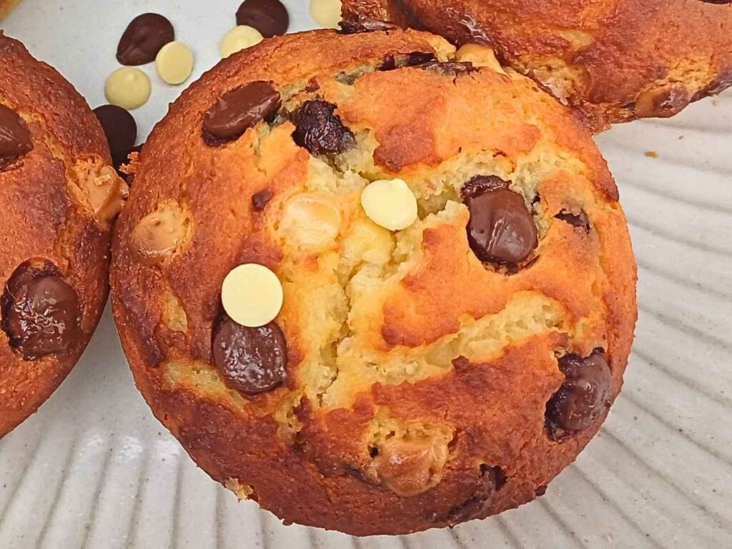 A homemade almond flour choc chip muffin with cracked top and golden edges