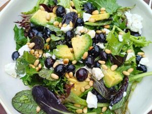 Goat cheese salad with blueberries and spring mix leaves with avocado and pine nuts in a bowl