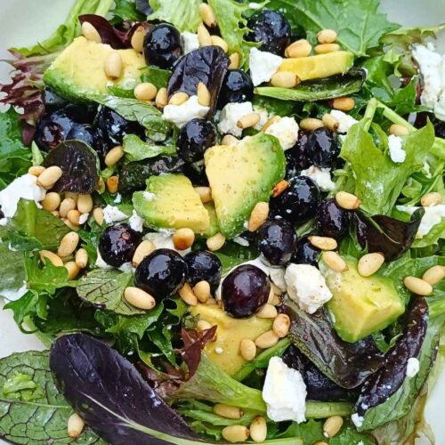 Goat cheese salad with blueberries and spring mix leaves with avocado and pine nuts in a bowl