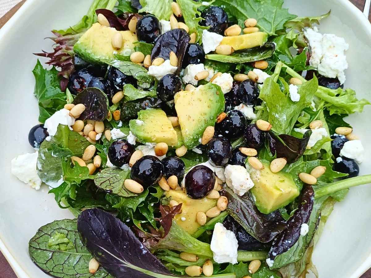 Goat cheese salad with blueberries and spring mix leaves with avocado and pine nuts in a bowl