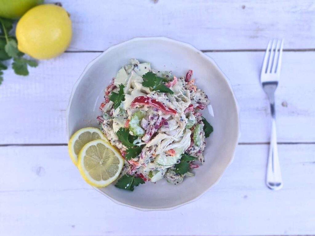 A bowl of high protein chicken salad with quinoa, red peppers, green apples and creamy yogurt dressing