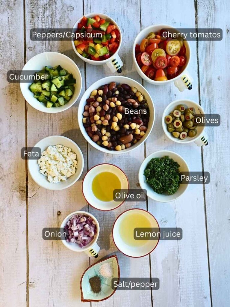 Ingredients for the dense bean salad layed out on a table in bowls