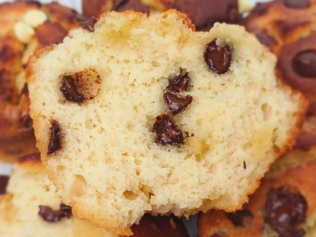 A broken open chocolate chip almond flour muffins showing melted chocolate chips inside