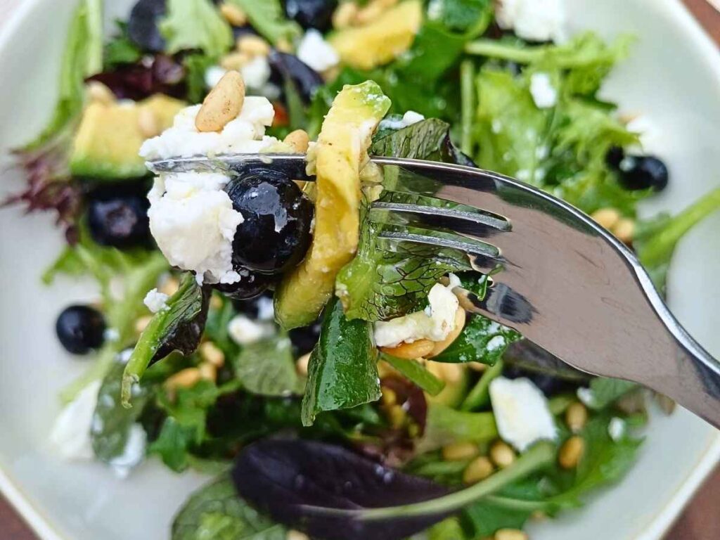 Blueberry and spring mix goat cheese salad on a fork