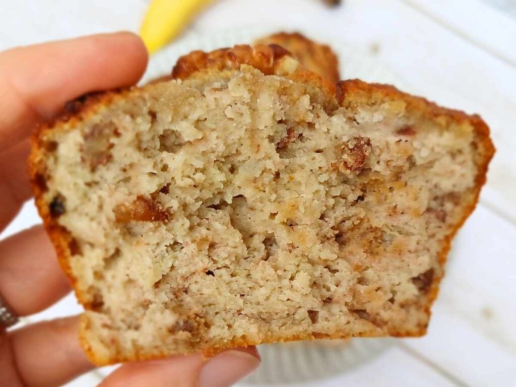 A broken banana nut muffins made with almond flour showing soft center with nuts