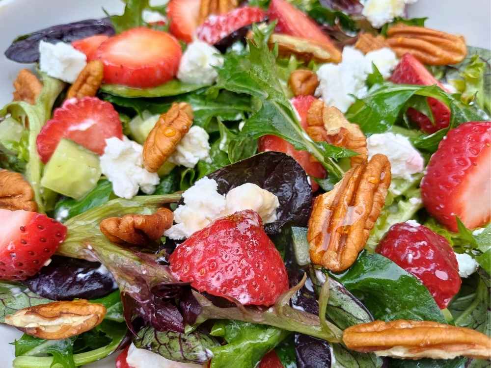 Strawberry feta salad with pecan nuts and mixed leaves close up