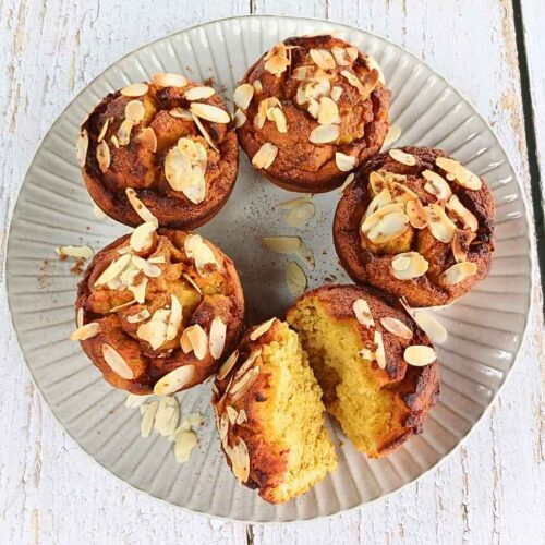A plate of almond flour pumpkin muffins with one broken to see inside