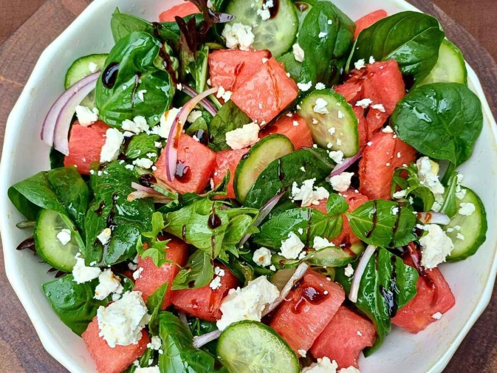 Watermelon feta salad in a bowl with spring mix salad leaves