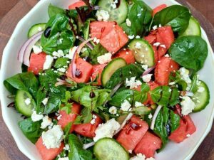 Watermelon feta salad in a bowl with spring mix salad leaves