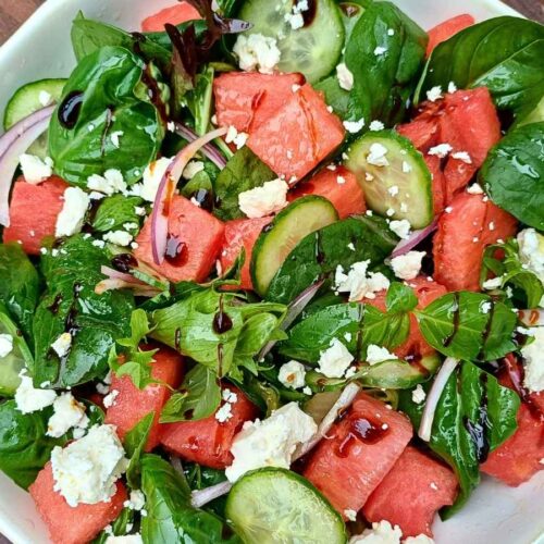Watermelon feta salad in a bowl with spring mix salad leaves