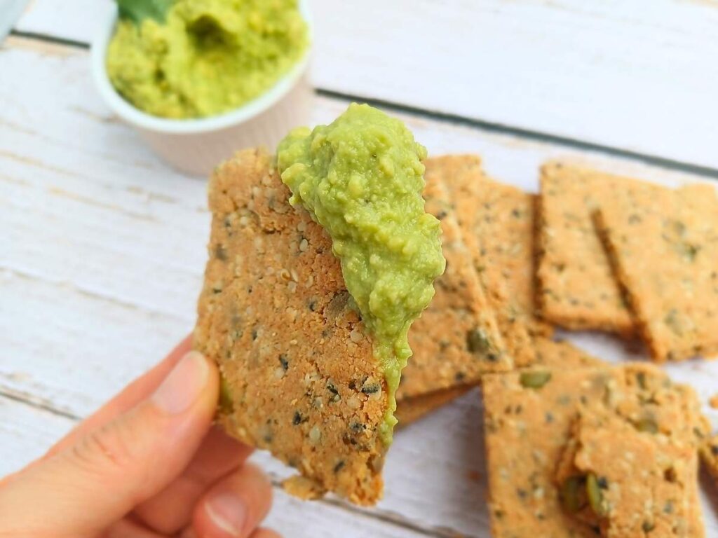 A homemade almond flour cracker dipped into avocado guacamole