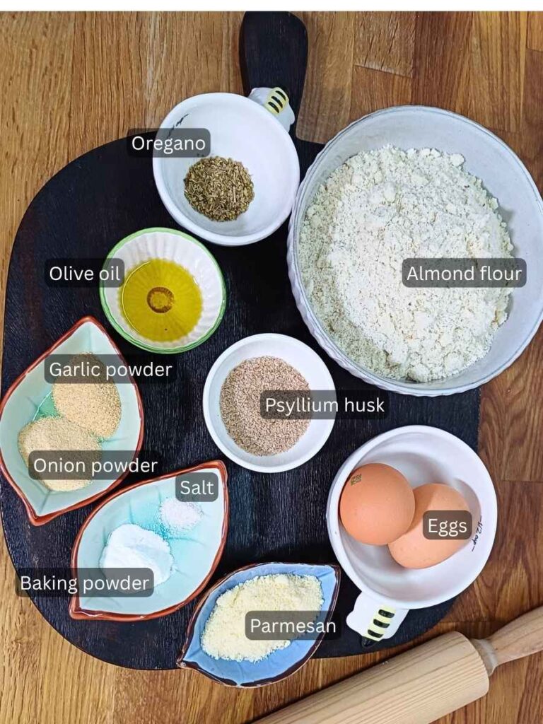 Ingredients for the almond flour pizza crust laid out on a board in bowls