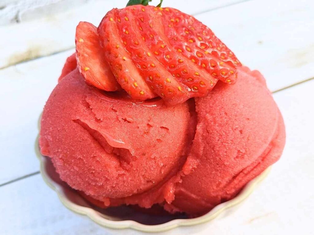 strawberry sorbet in a cup with fresh strawberries on top