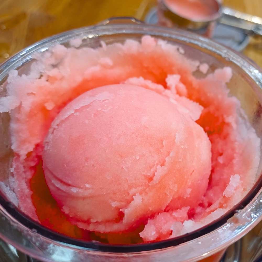 A scoop of watermelon sorbet in a pint