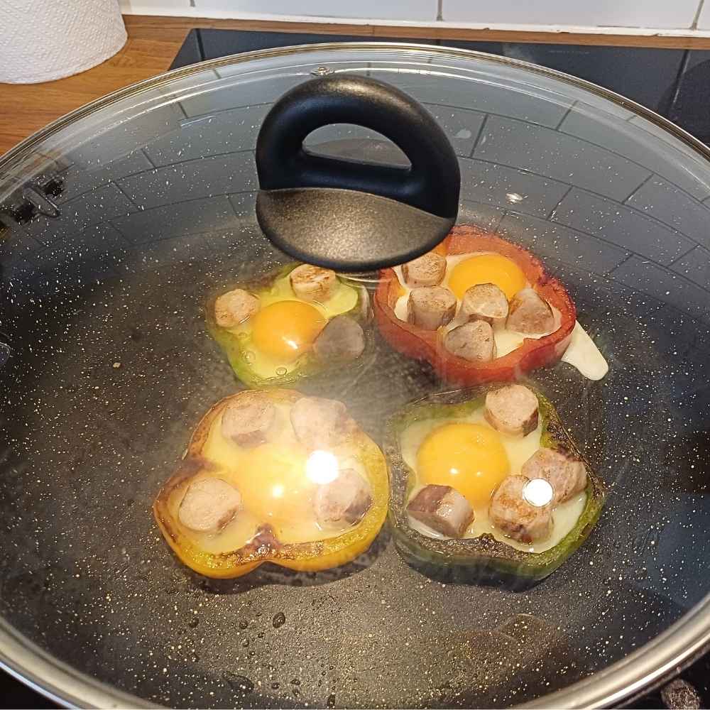 bell pepper egg rings with sausage on a skillet covered with lid