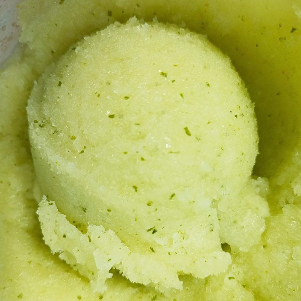 scoop of lemon sorbet Ninja Creami with lime and mint in a pint