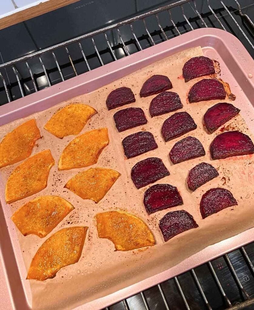Roasted pumpkin and beet pieces on a baking sheet