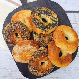 Eight homemade cottage cheese bagels on a dark wooden board