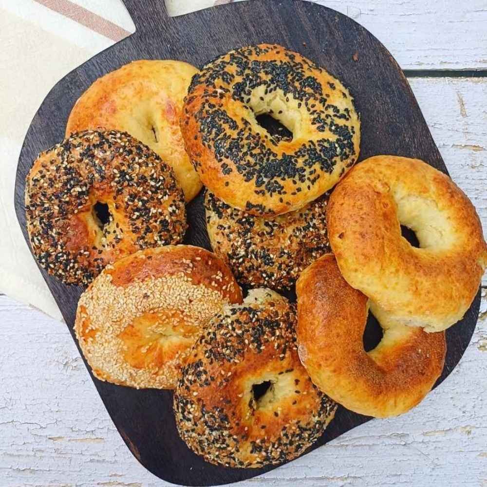 Eight homemade cottage cheese bagels on a dark wooden board